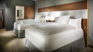 A hotel room with two beds, a large mirror, a wooden headboard, and a carpeted floor.
