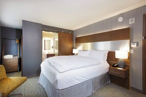 A hotel room with a large bed, a bedside table with a lamp, a chair, a wardrobe, and a mirror. - Hotel Z (San Diego)