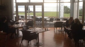A restaurant with large windows, tables, and chairs. - East Pier Hotel (Napier)
