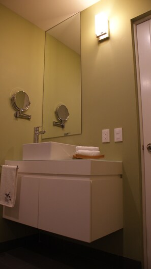 Une salle de bain avec un lavabo blanc, deux miroirs et un porte-serviettes.