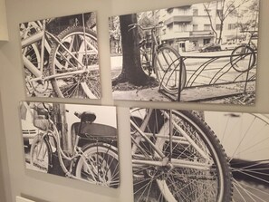 Un mur orné de quatre photographies en noir et blanc représentant des bicyclettes.