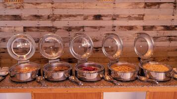 A buffet with multiple food containers, each with a lid, on a counter against a wooden wall.