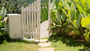 A pathway leading to a white gate with lush greenery and mountains in the background. - El Nido Bayview Resort (El Nido)