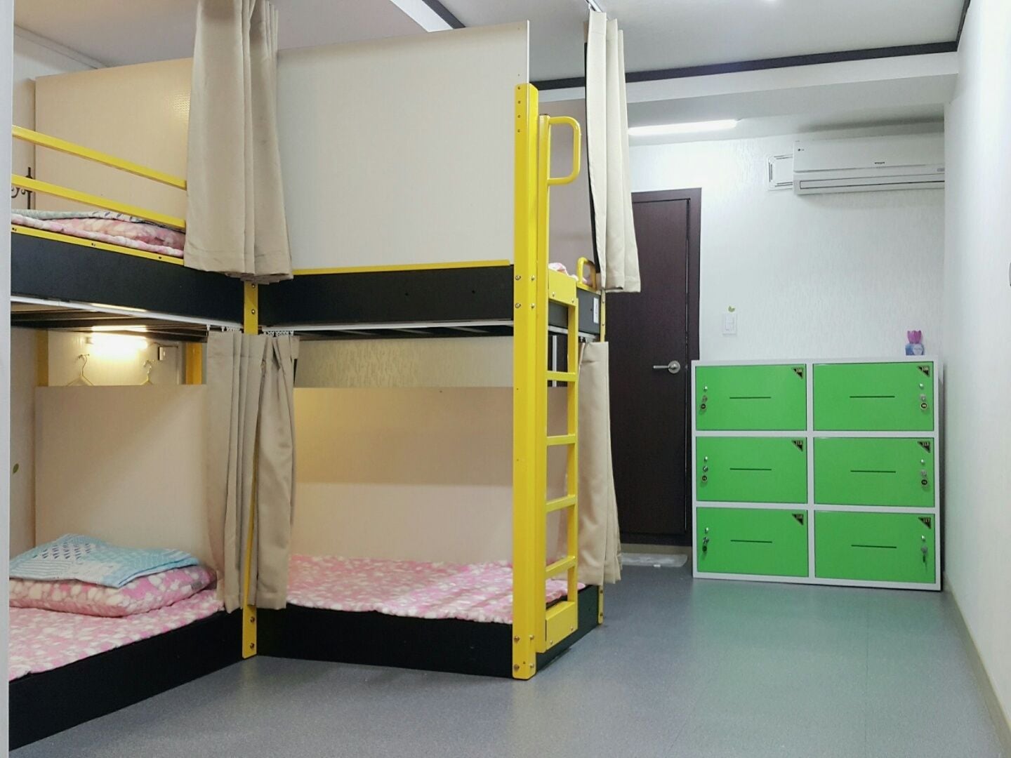 A bunk bed room with a ladder, a door, and green storage cabinets.