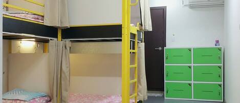 A bunk bed room with a ladder, a door, and green storage cabinets.