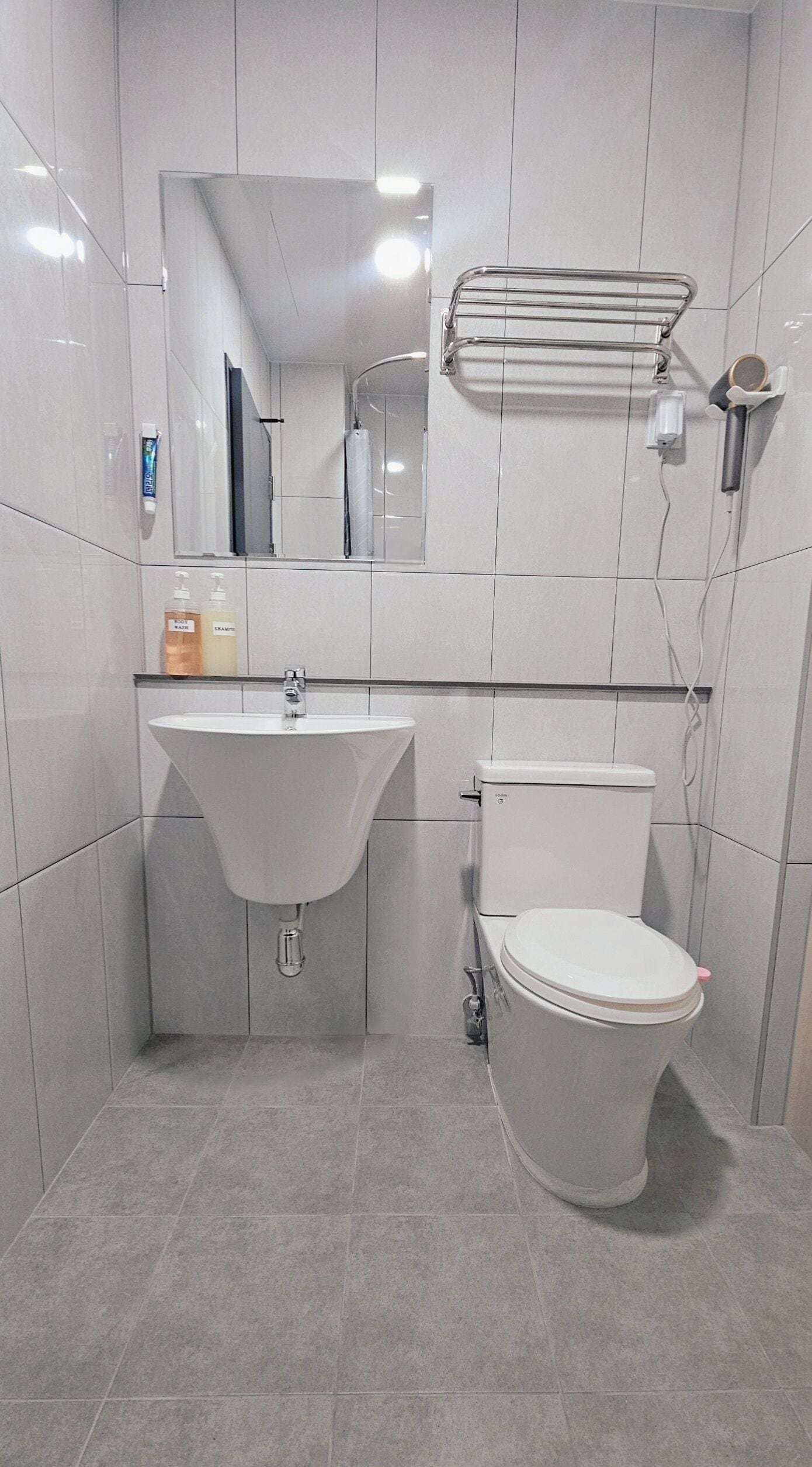 A modern bathroom with a sink, toilet, and a towel rack.