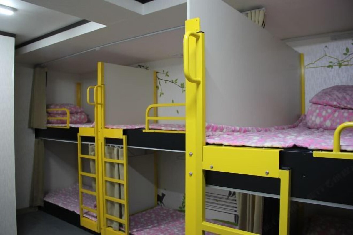 A bunk bed room with yellow railings and pink bedding.