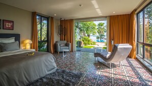 Habitación de hotel con una cama grande, dos sillones, una mesita y vistas al exterior.