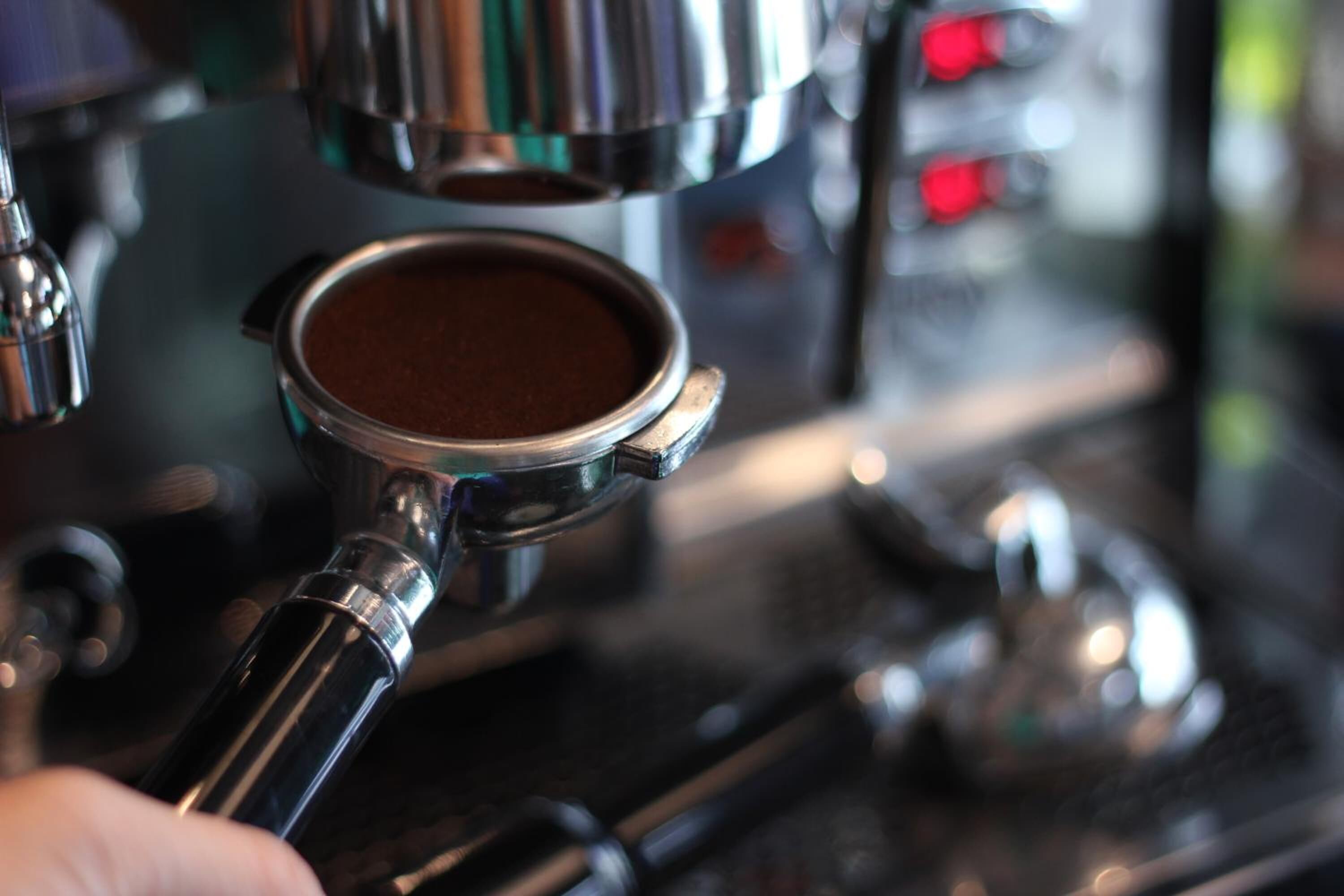A close-up of a coffee machine with a portafilter filled with coffee grounds.
