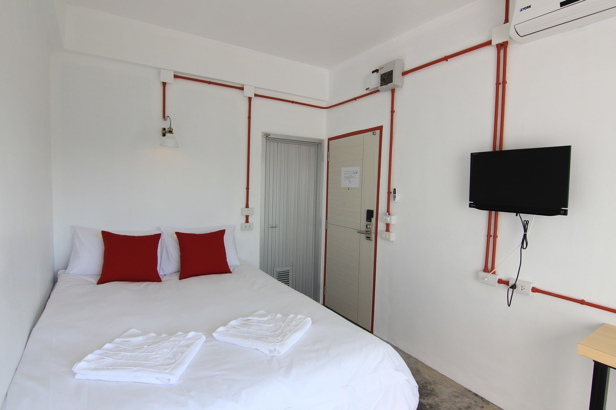 A hotel room with a bed, a TV mounted on the wall, and a door leading to a bathroom.