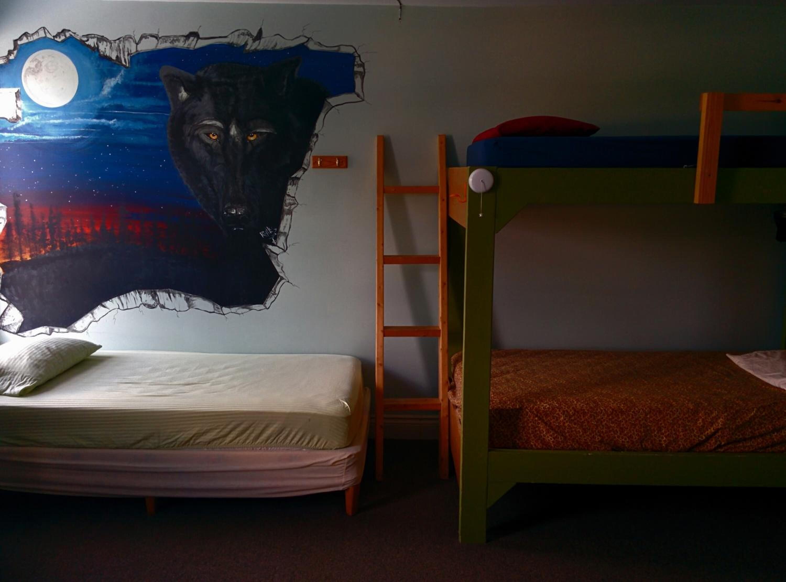 A bunk bed room with a wall mural of a wolf and a moon.