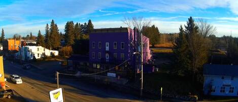 A street view with a purple building, a white building with a sign, and a yellow signboard.