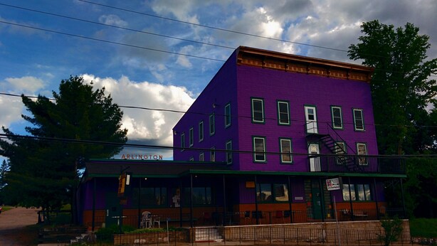 A purple building with a sign reading "ARLINGTON" and a staircase leading to a balcony.