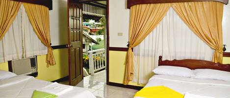 A hotel room with two beds, a balcony, and a view of a residential area.