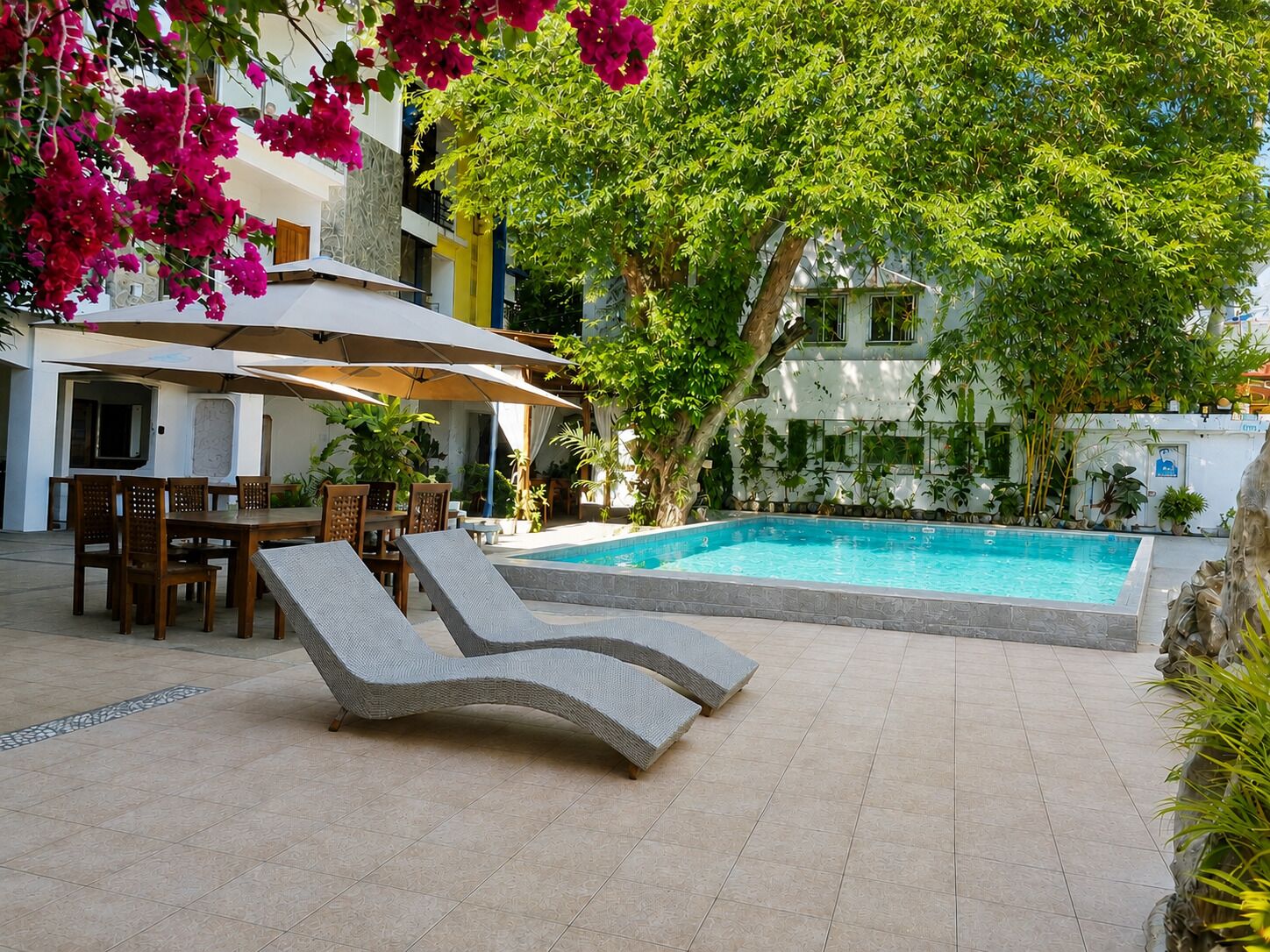 A poolside area with lounge chairs, a dining table, and umbrellas.