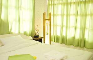 Ein Hotelzimmer mit Bett, grünen Vorhängen, einem Nachttisch mit Dekoration und einer Wand mit strukturierter Oberfläche.
