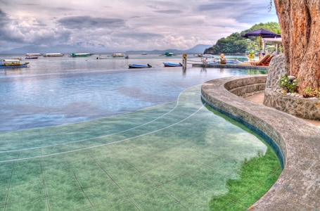 Una piscina al aire libre, sombrillas, sillones reclinables de piscina