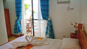 Habitación de hotel con una cama, una ventana con cortinas, una mesita con un florero y vistas al exterior.