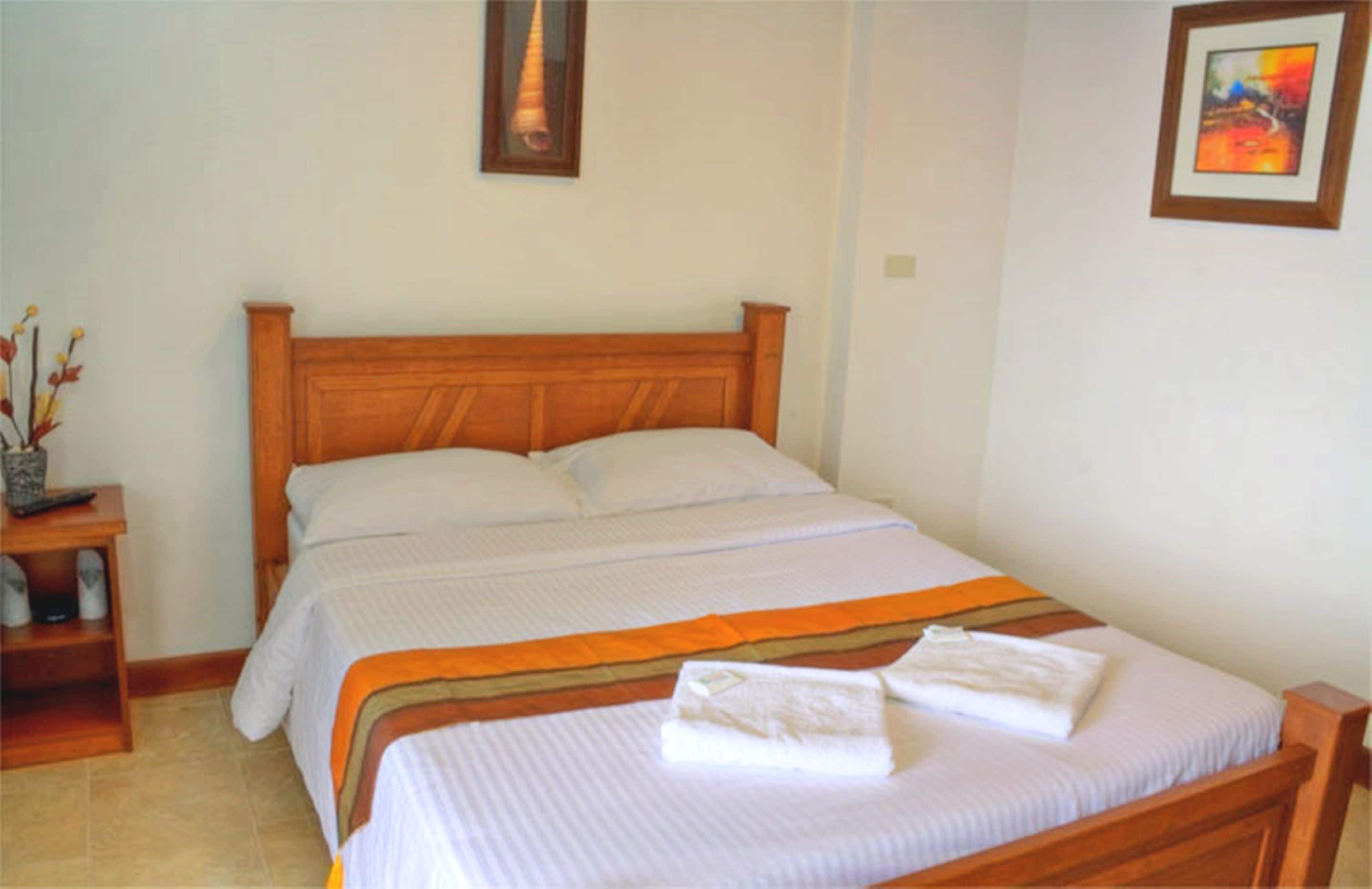 A double bed with a wooden headboard, white bedding, and a striped blanket.