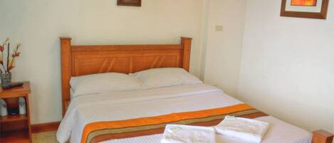 A double bed with a wooden headboard, white bedding, and a striped blanket.