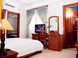 Een hotelkamer met een bed, een bureau met stoel, een televisie en een spiegel.