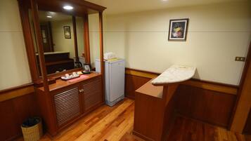A compact kitchen with wooden cabinets, a refrigerator, a sink, and a mirror.