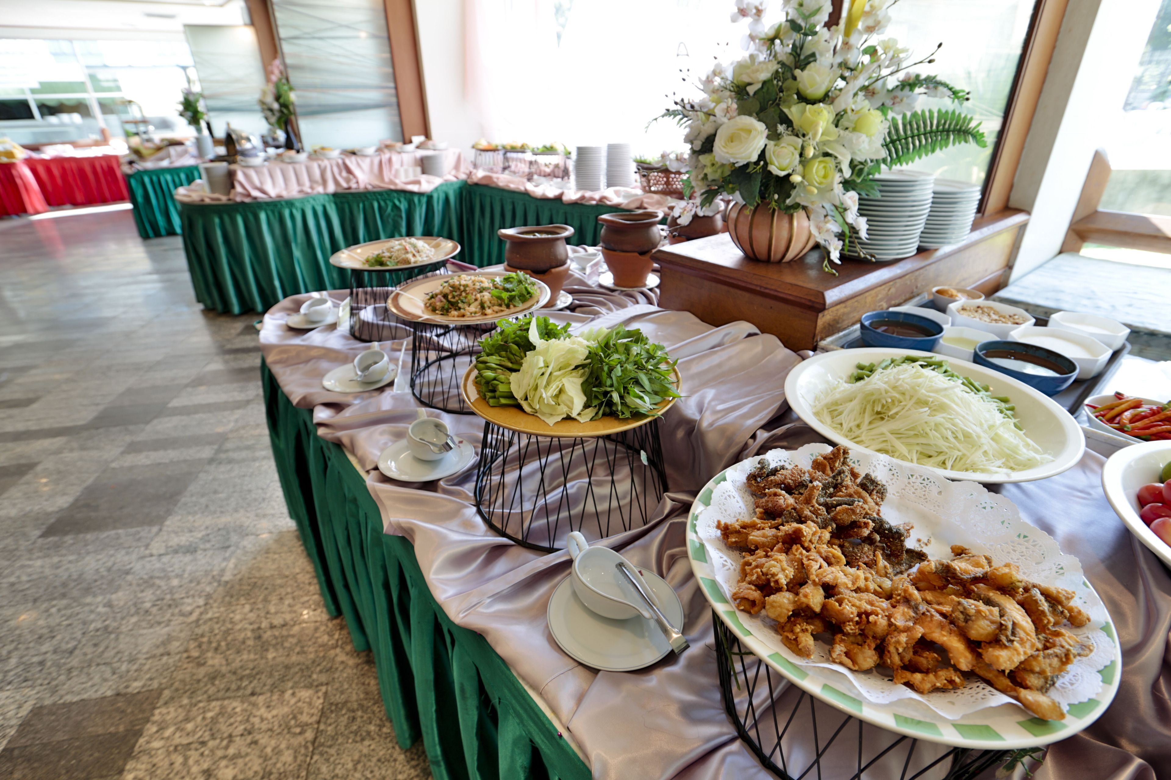 A buffet table with various dishes and a floral arrangement.