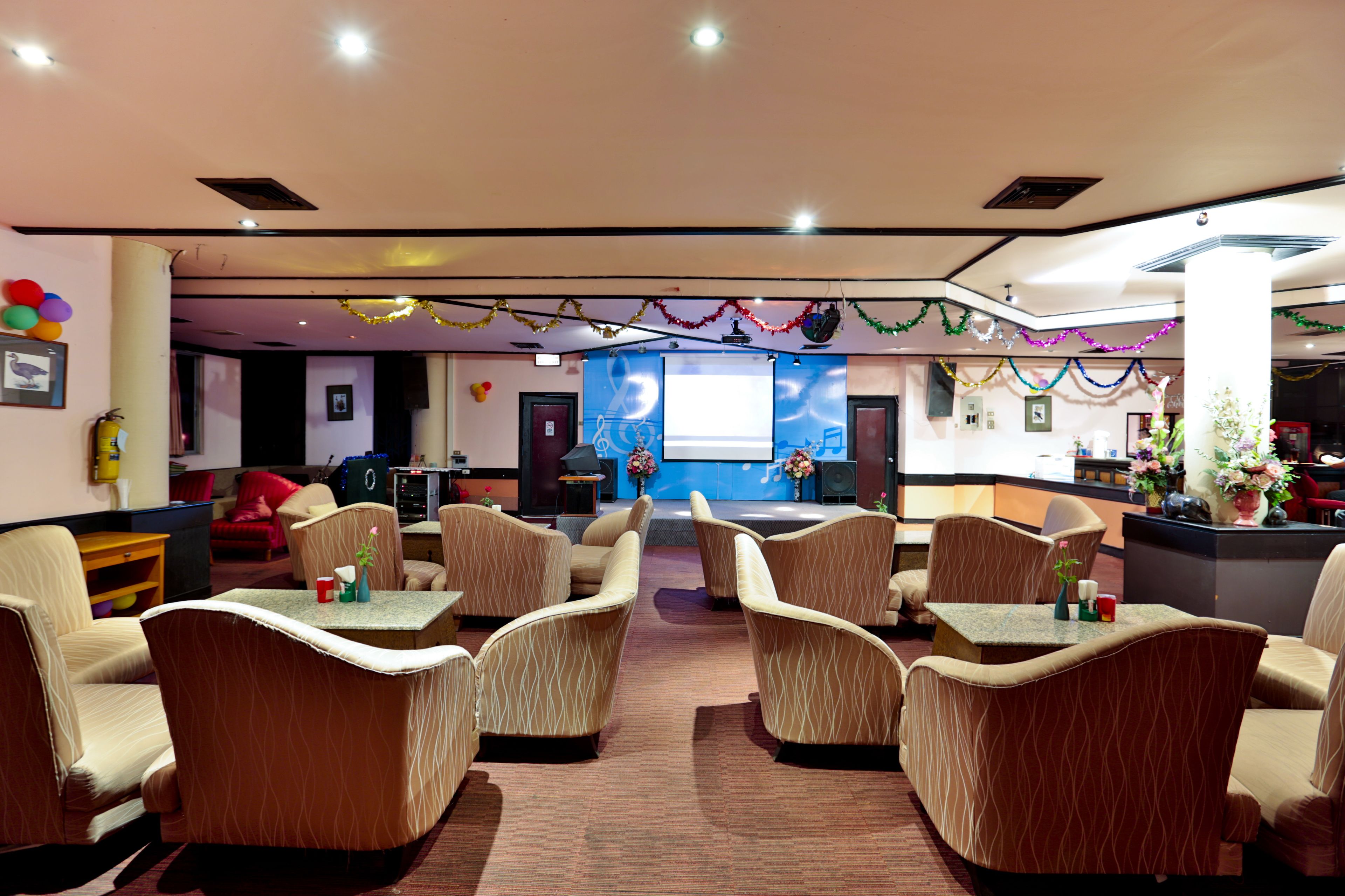 Een hotelhal met een podium, zachte zitplaatsen en feestelijke decoraties.