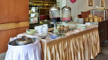 A buffet setup with various food containers, plates, and utensils.