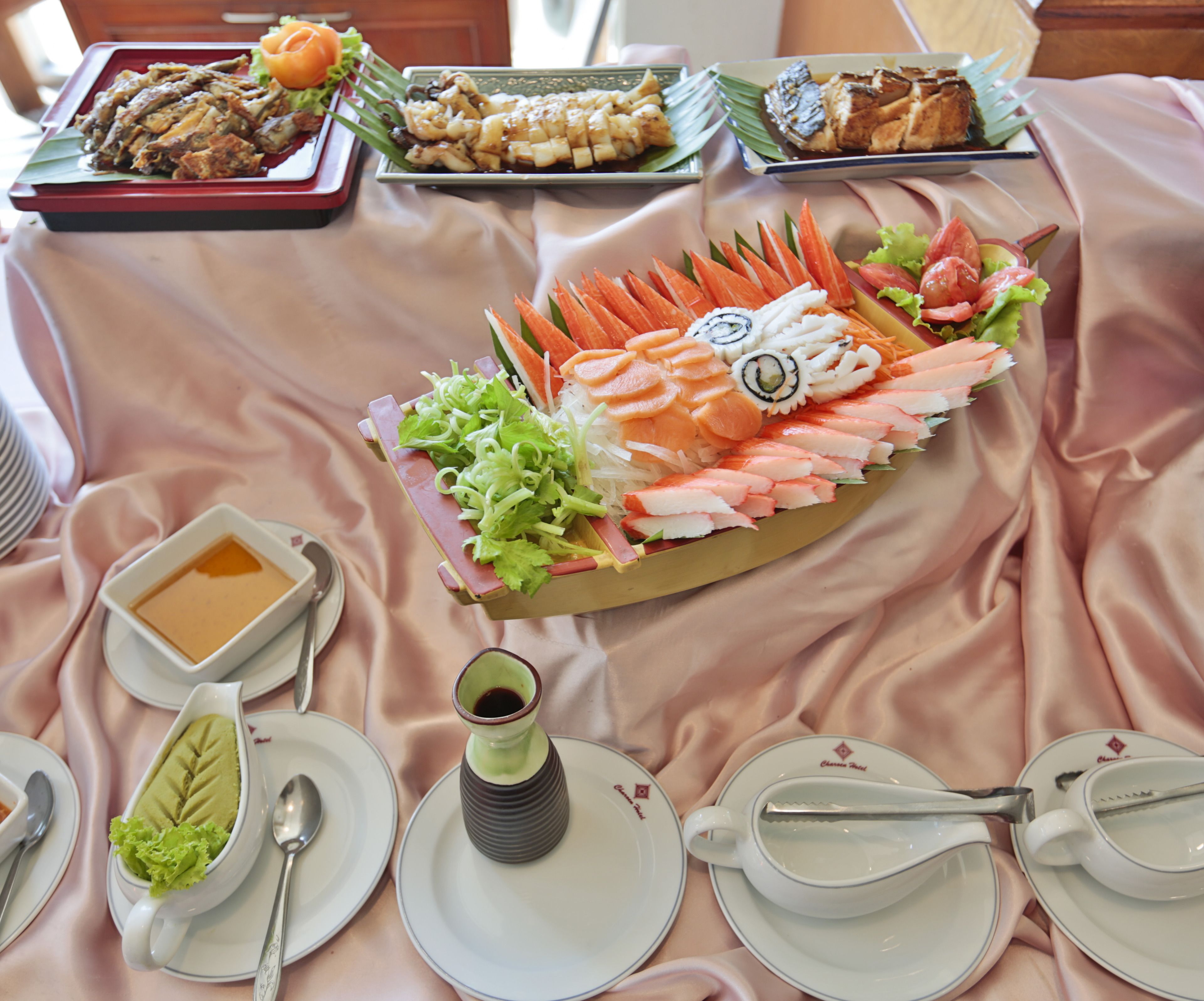 A table with a variety of dishes, including sushi, sashimi, and a bowl of soup.