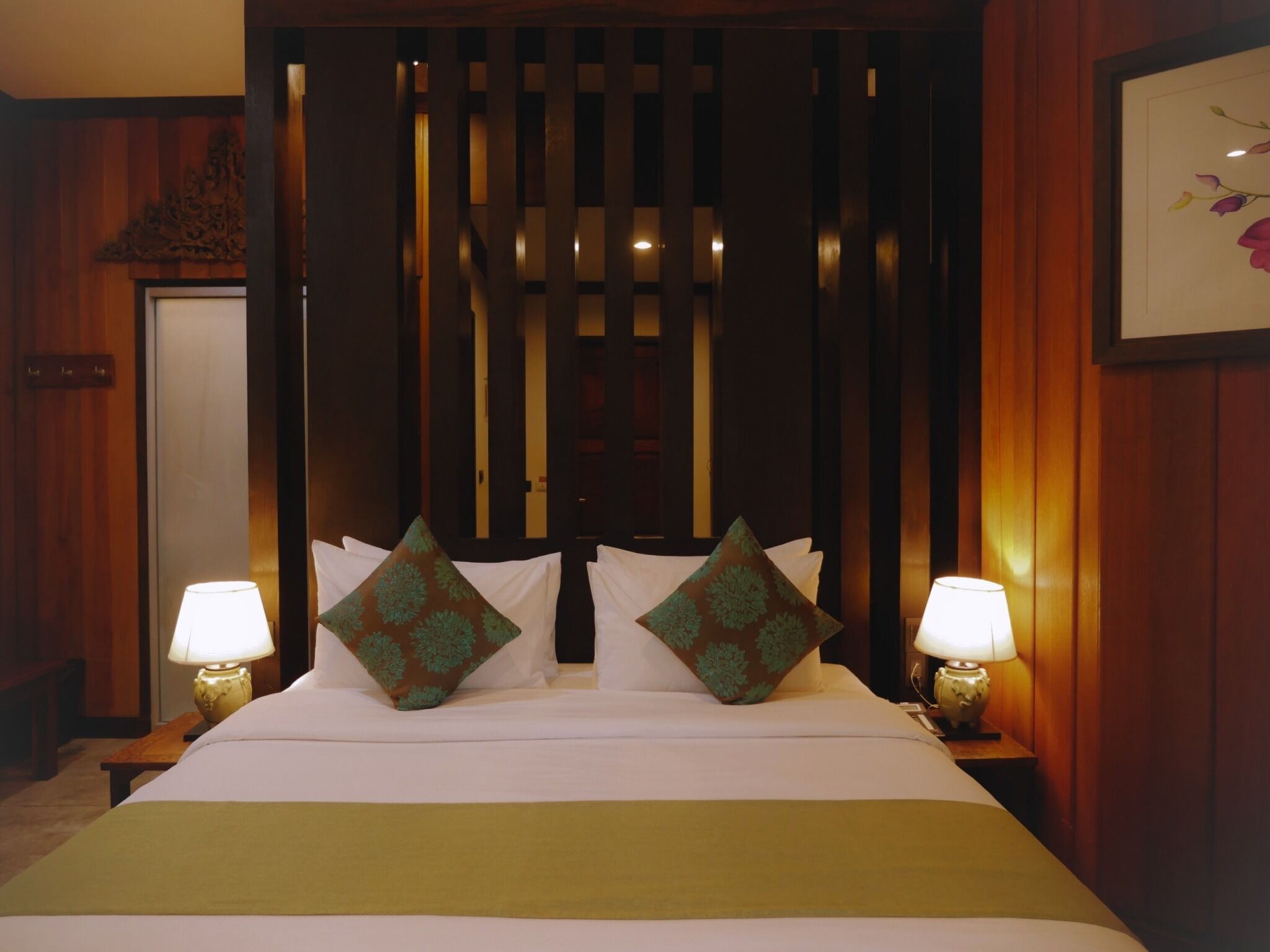 A hotel room with a bed, two bedside lamps, and a decorative panel.