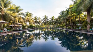 Ein Pool mit Palmen und Liegestühlen.
