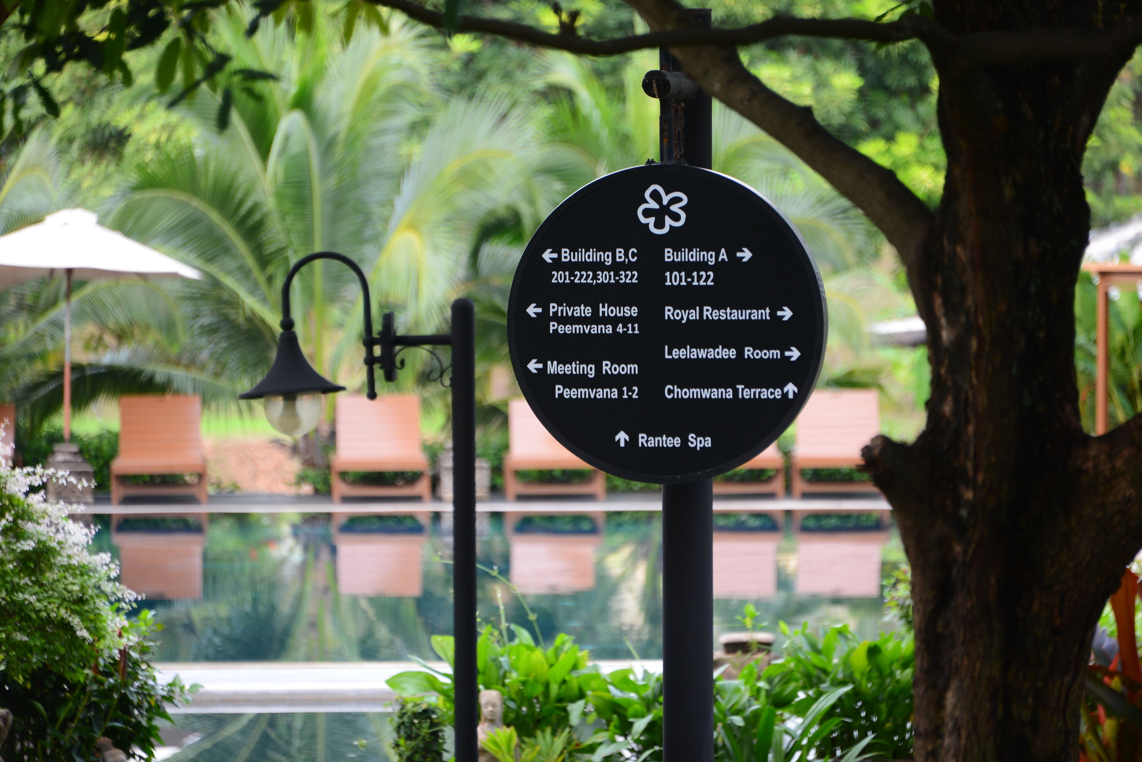 Ein Schild mit Wegweisungen zu verschiedenen Hotelbereichen, darunter Gebäude B/C, Private House, Konferenzraum, das Royal Restaurant, der Leelawadee-Saal und das Rantee Spa.