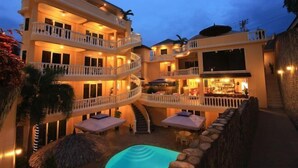A multi-story hotel with balconies, a pool, and outdoor seating. - Mermaid Resort and Dive Center (Puerto Galera)