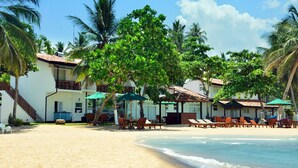Een strandhotel met meerdere kamers, terrasjes en palmbomen.
