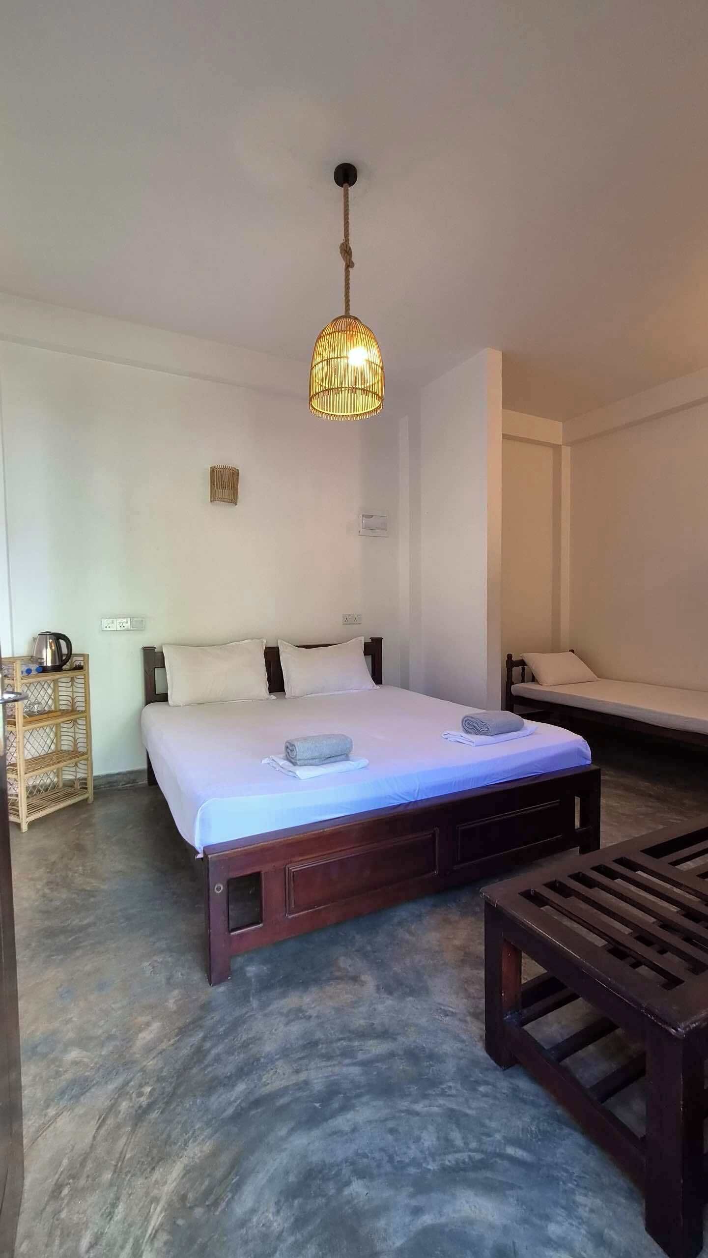 Un dormitorio con cama, mesita de noche y lámpara colgante.