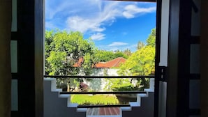 A view through a window with a white frame, reflecting greenery and a red-roofed building. - Riverside Cabanas (Mirissa)