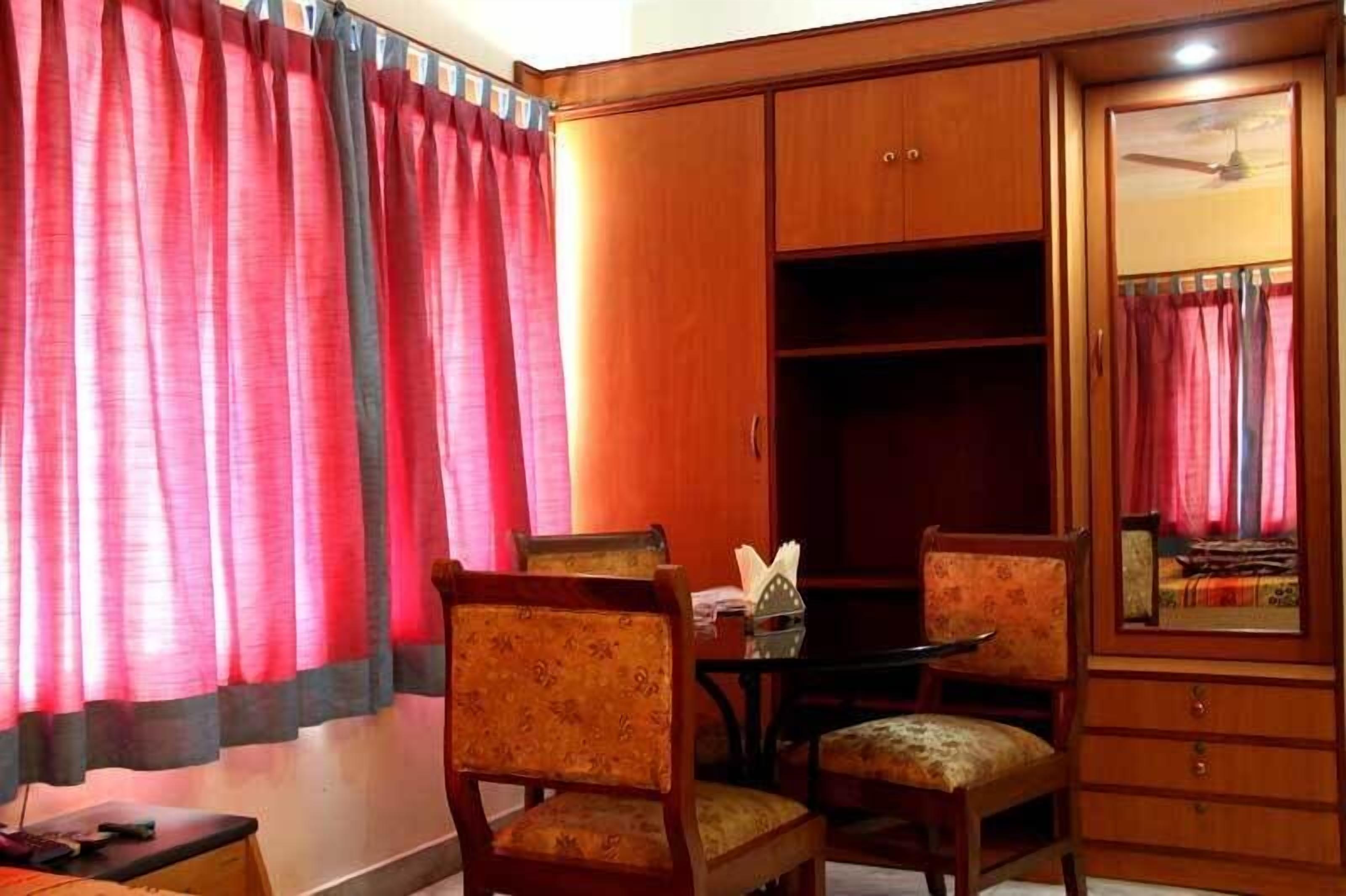 Una habitación con un armario de madera, una mesa de comedor con sillas y un espejo.