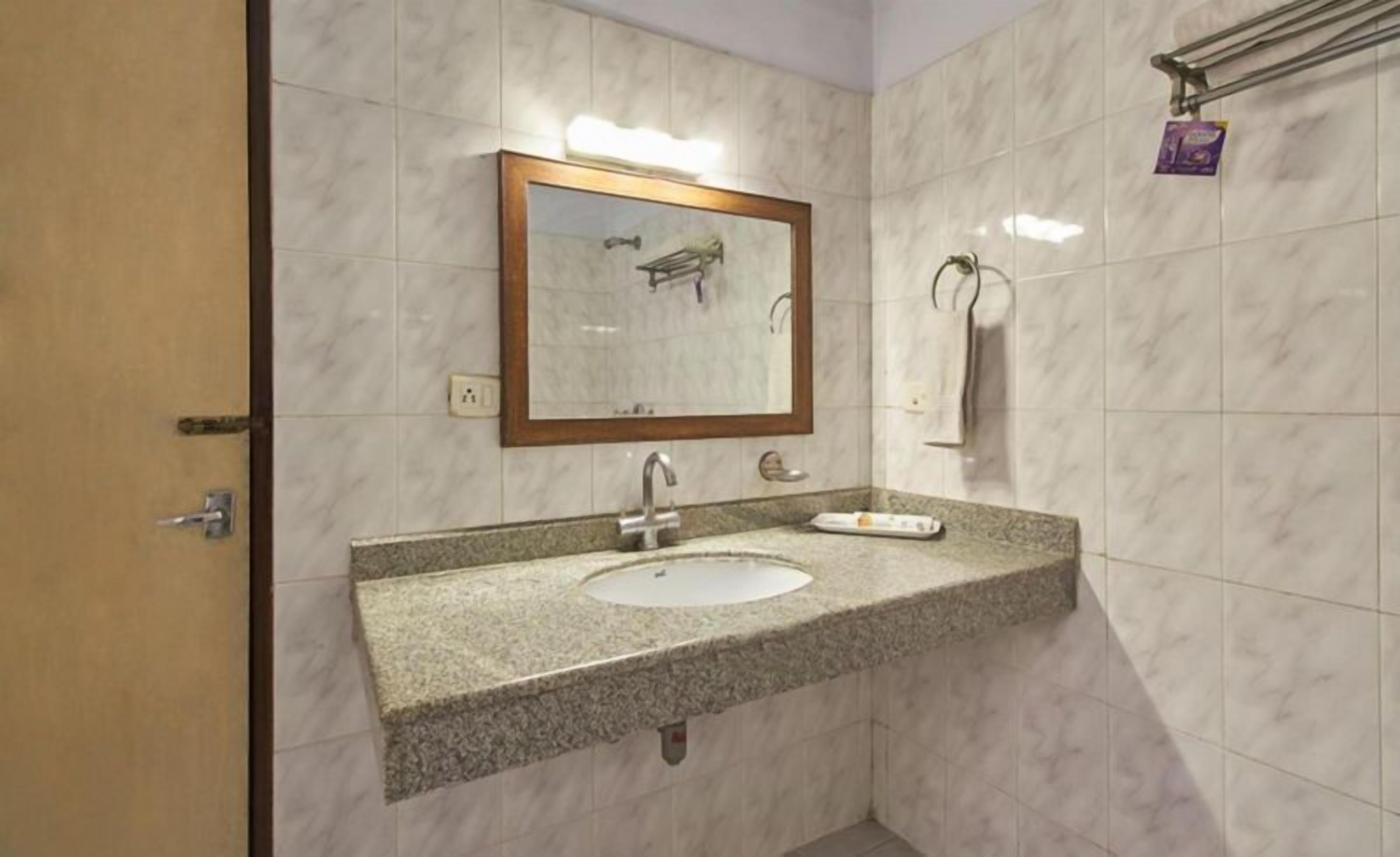 A bathroom with a double sink, a mirror with a wooden frame, and a towel rack.