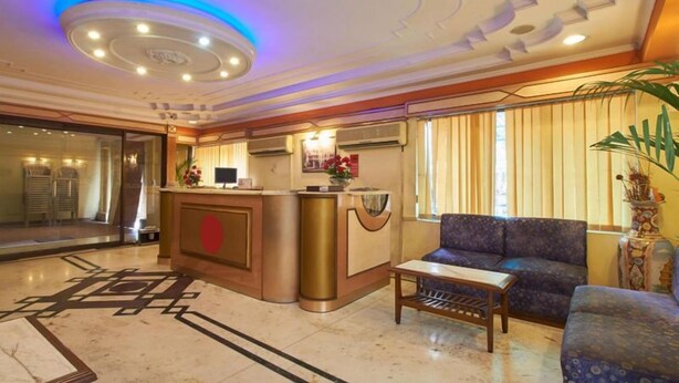 Una hall d'albergo con reception, area salotto e elementi decorativi.
