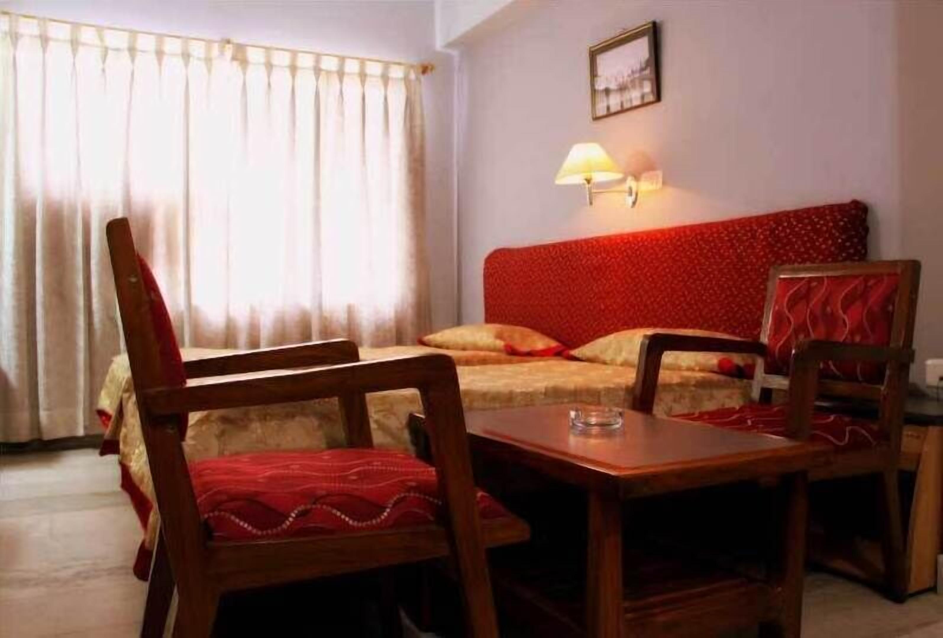 A room with a bed, a table, and two chairs.