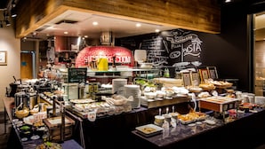 Zona de buffet con diferentes opciones de comida y un horno de pizza al fondo.