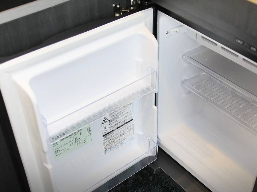 An open refrigerator with a clear shelf and a label on the door.