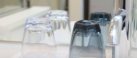 A set of clear glass tumblers on a white countertop, with a modern faucet to the right.
