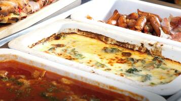 A buffet with various dishes including a quiche, roasted vegetables, and a pasta dish.
