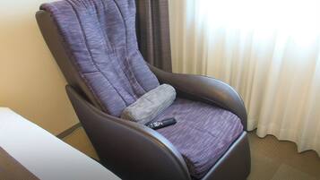 A recliner chair with a patterned fabric, a remote control on the seat, and a logo for Daiwa Roynet Hotels.