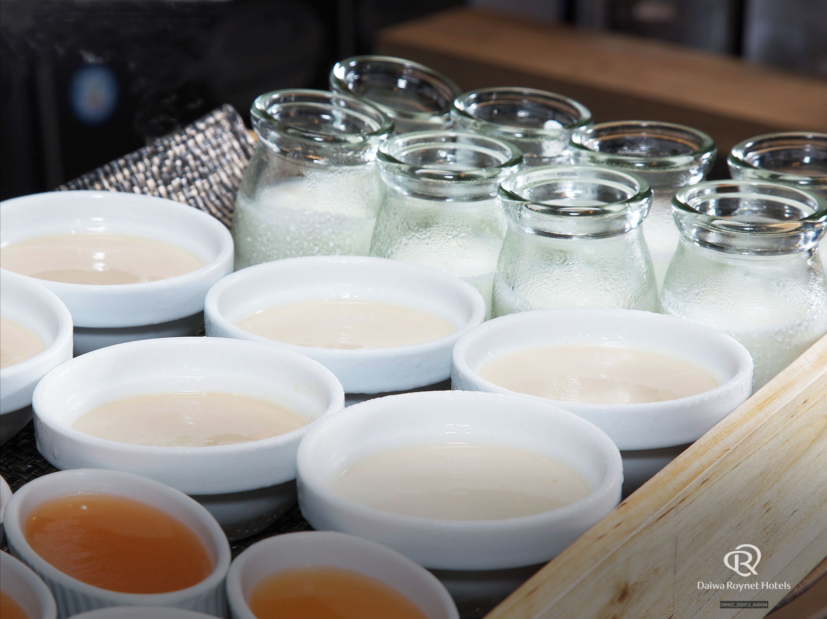 A variety of bowls and jars containing different colored liquids, likely condiments or dips, arranged on a table.