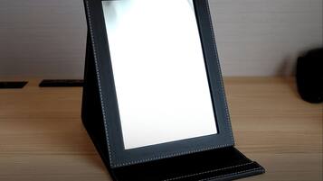 A black, leather-bound frame with a white display, placed on a wooden surface.