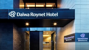 Exterior del hotel Daiwa Roynet, con un diseño moderno, que presenta un letrero llamativo y la entrada.