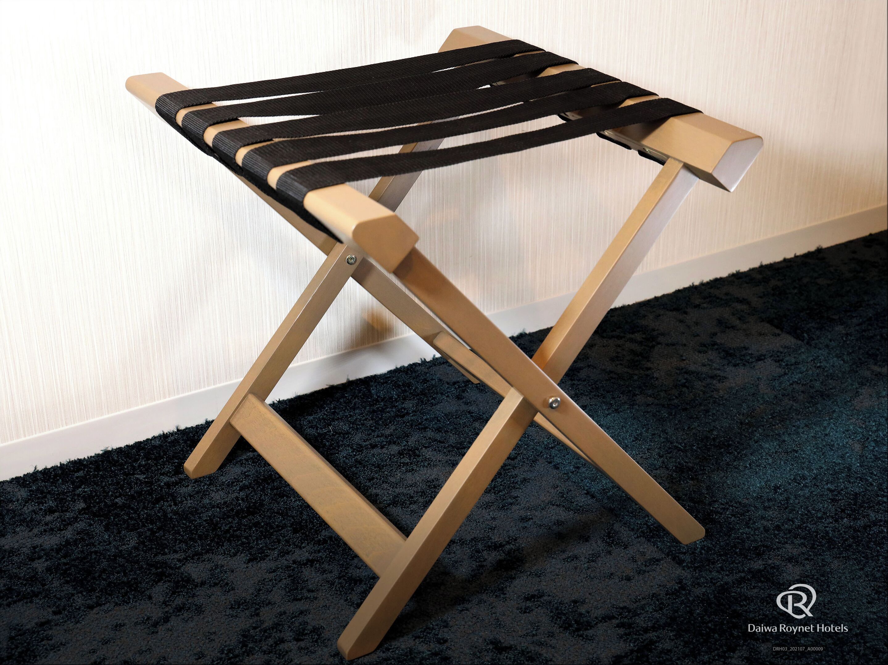A wooden stool with black straps.